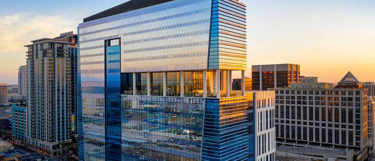 Glass high-rise hotel tower reflecting sunset light in downtown Orlando.